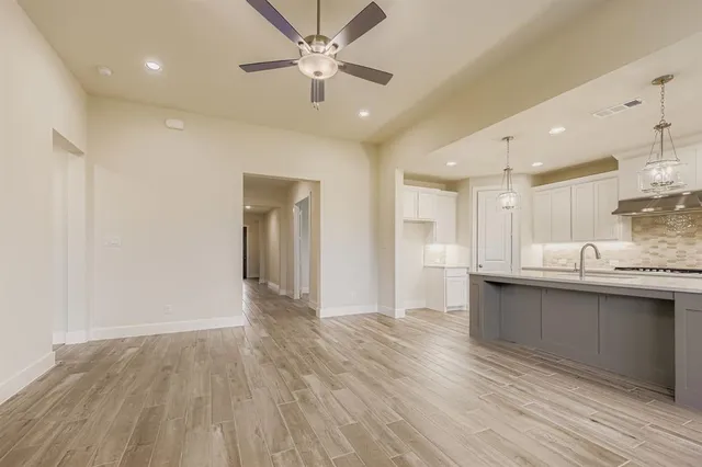 a kitchen with stainless steel appliances granite countertop a stove top oven a sink dishwasher and a fireplace with wooden floor