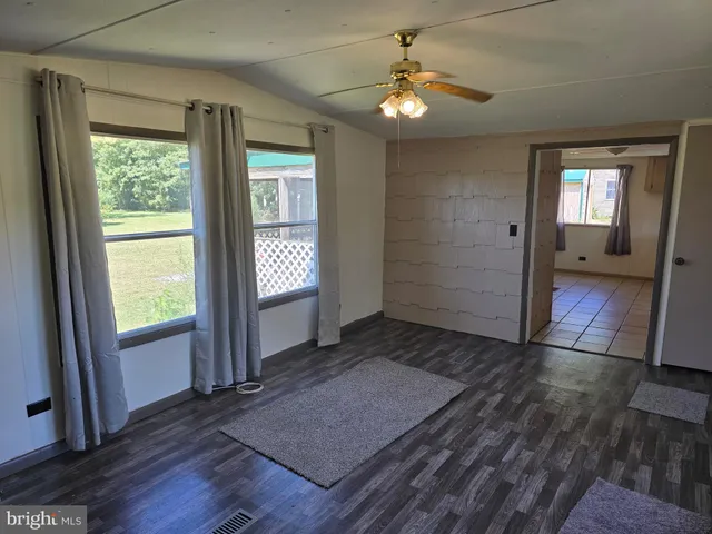 an empty room with wooden floor mirror and windows