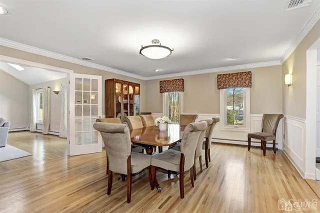 a dining room with wooden floor a chandelier a glass table and chairs