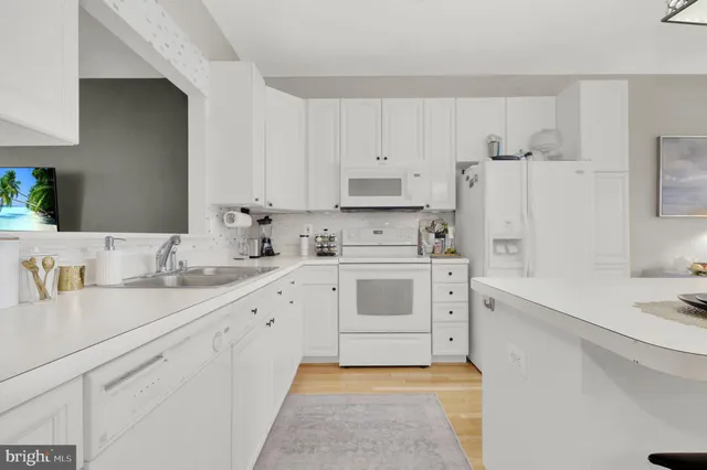 a kitchen with stainless steel appliances kitchen island a table chairs in it and white cabinets