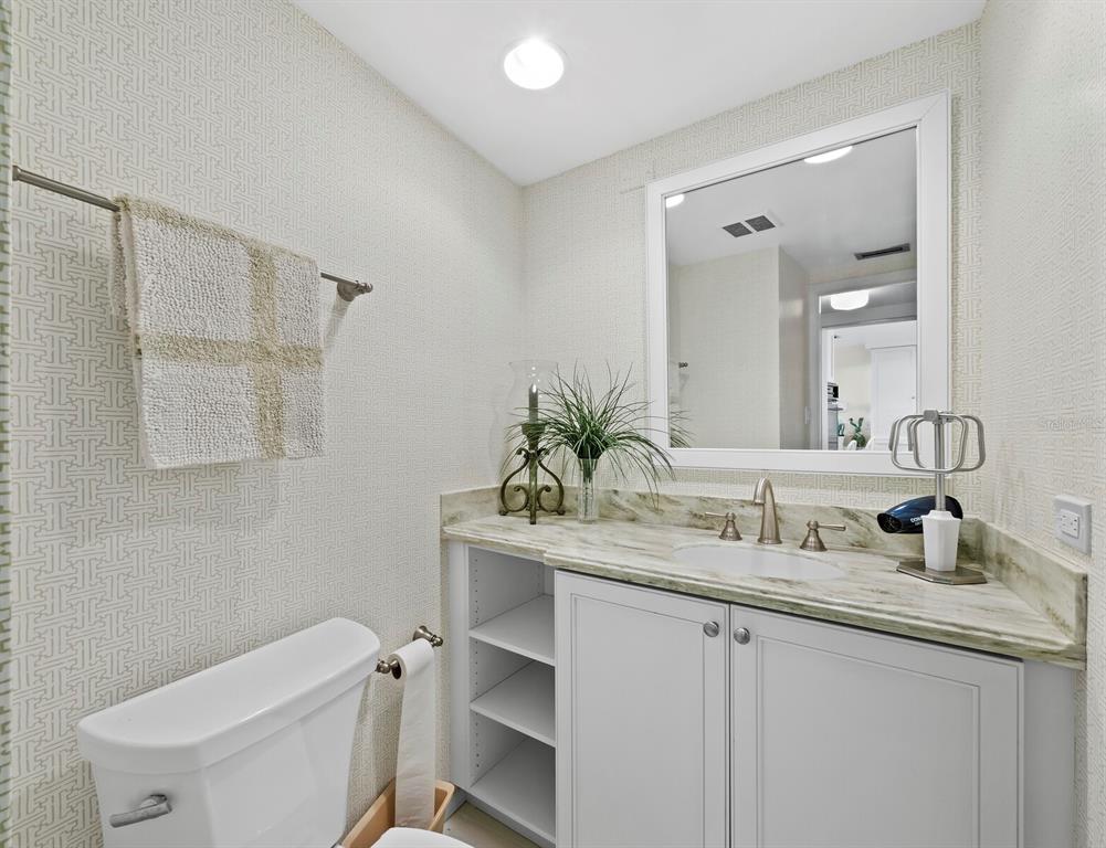 100 Sands Point Road, Unit 108 Longboat Key, FL 34228 - Photo 27 of 46 a bathroom with a granite countertop sink a toilet and mirror