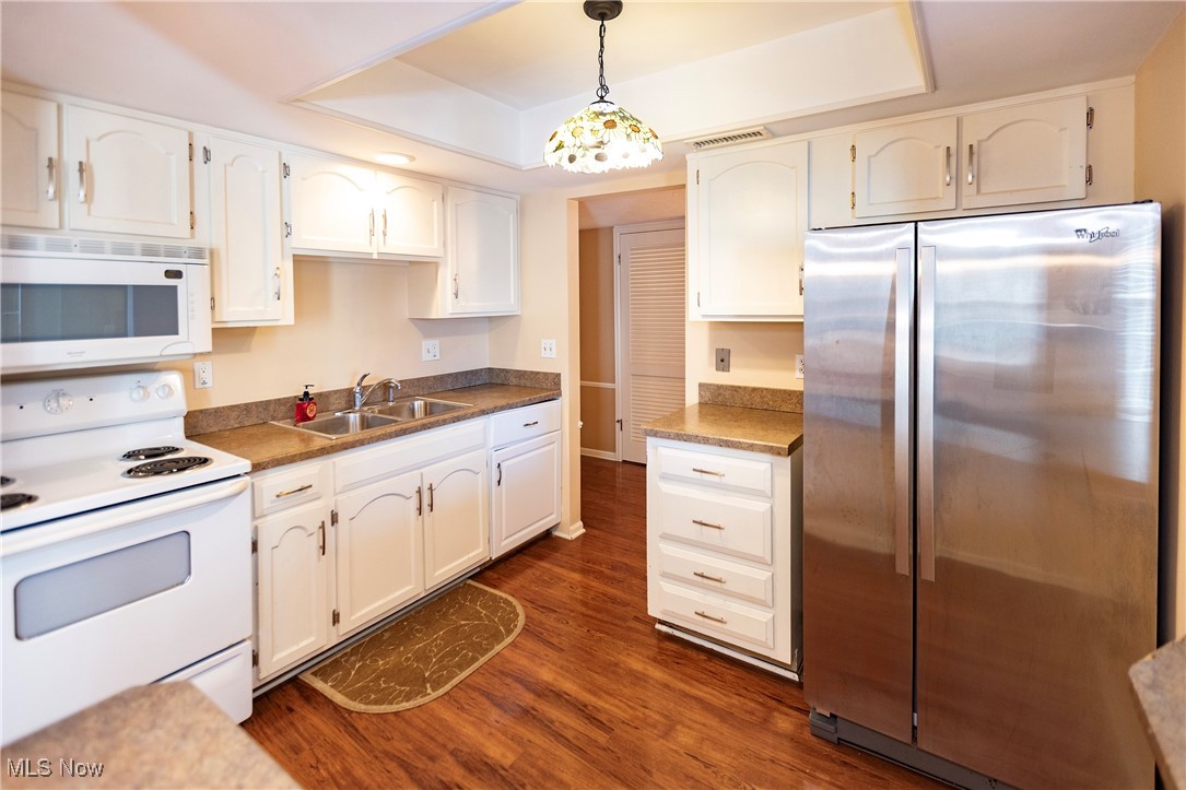 22701 Center Ridge Road, Unit 307 Rocky River, OH 44116 - Photo 14 of 27 Kitchen featuring white appliances, hanging light fixtures, a tray ceiling, and white cabinets