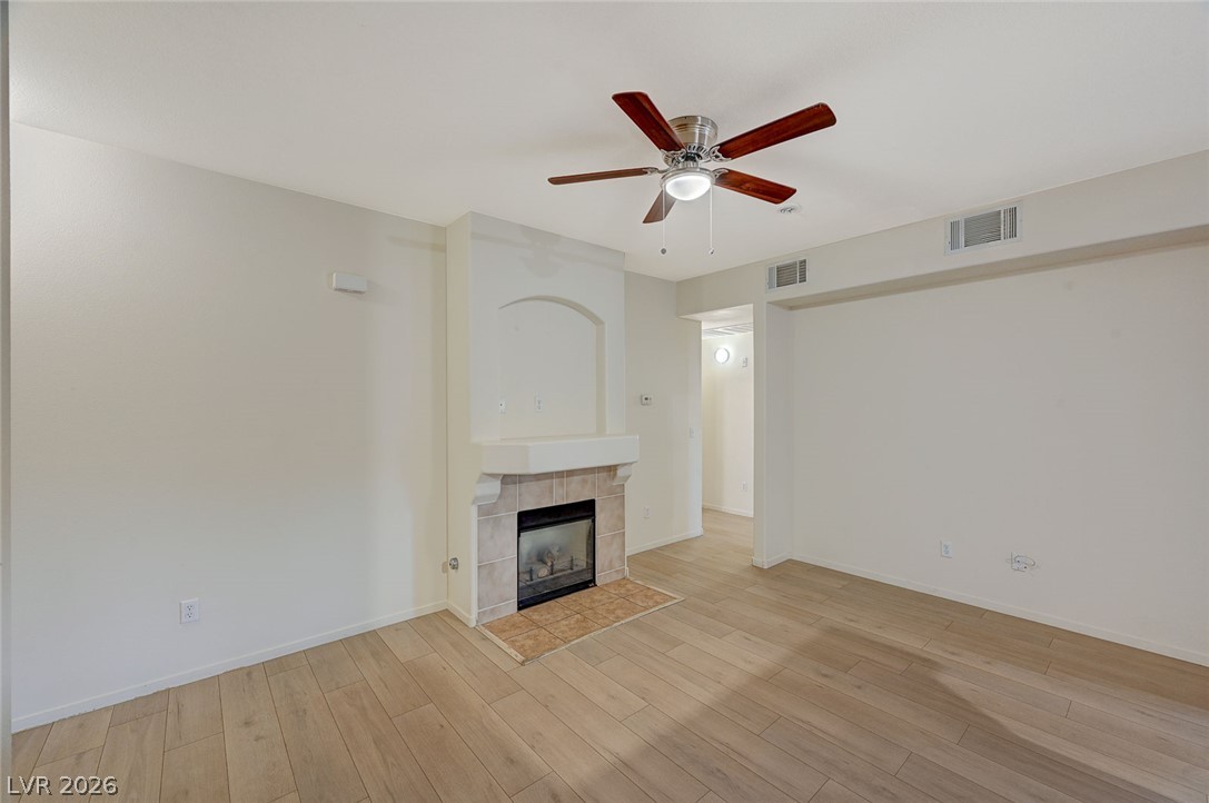 9050 West Warm Springs Road, Unit 1147 Las Vegas, NV 89148 - Photo 6 of 36 Warm wood-look flooring complements the inviting fireplace, creating a cozy living space.