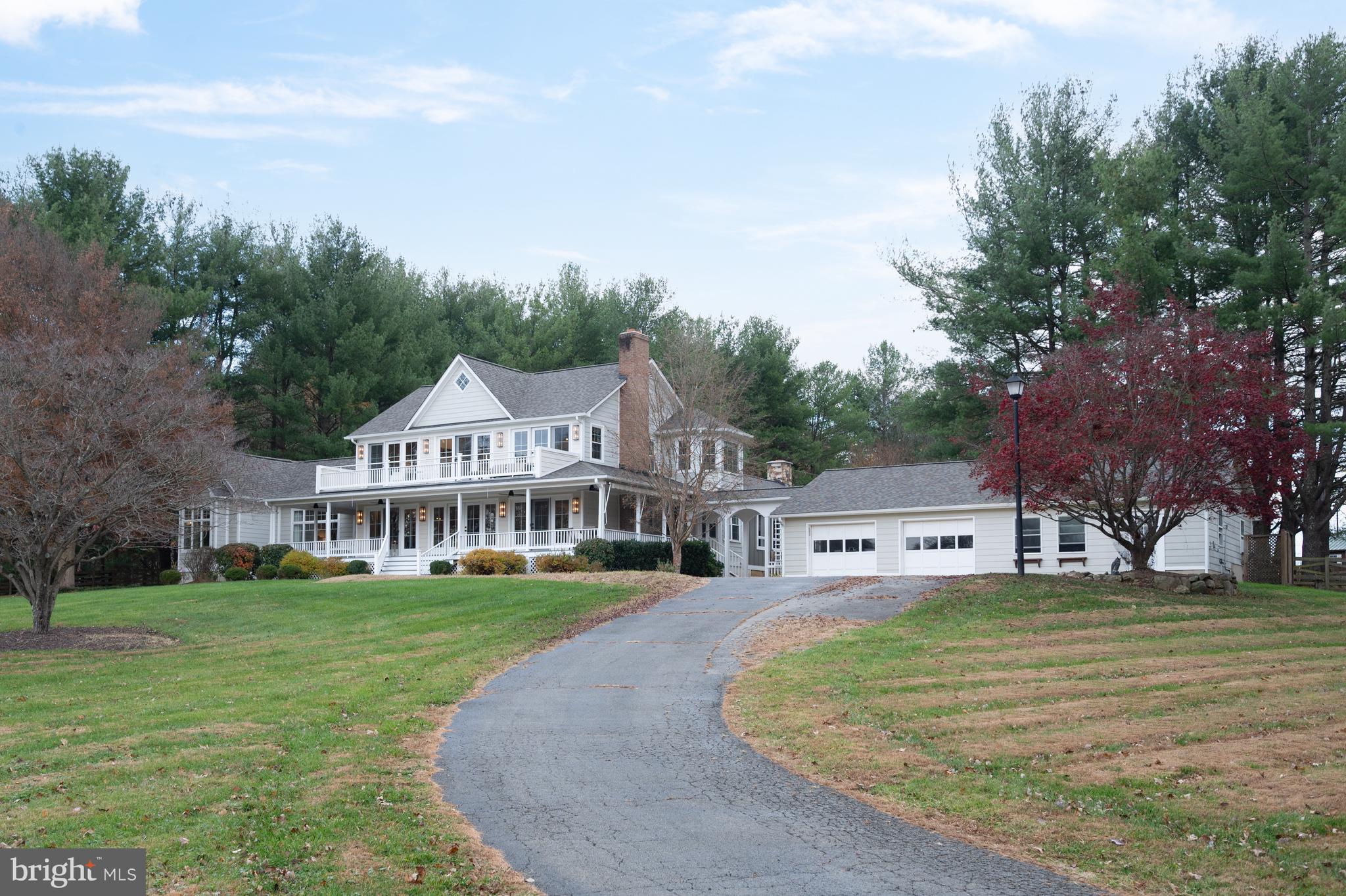 37896 Legard Farm Road Purcellville, VA 20132 - Photo 5 of 117 a view of a white house in front of a big yard with plants and trees