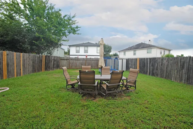 a view of a backyard with table and chairs and wooden fence