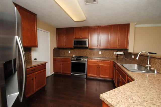 a kitchen with granite countertop wooden cabinets and stainless steel appliances