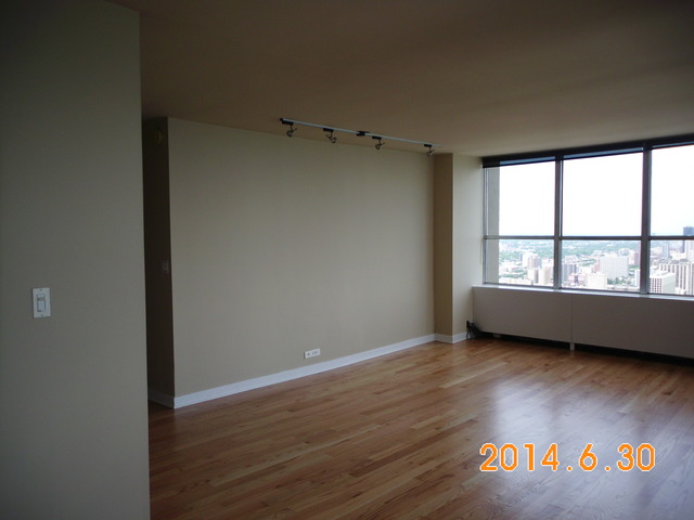 655 West Irving Park Road, Unit 4910 Chicago, IL 60613 - Photo 3 of 22 an empty room with wooden floor and windows