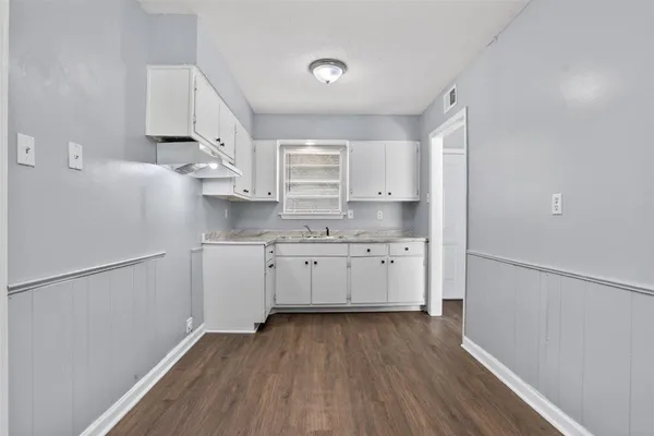 a kitchen with a white cabinets and wooden floor