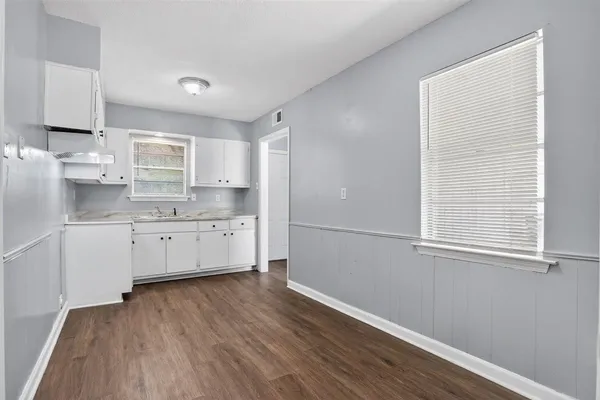 a kitchen with wooden floors and white cabinets