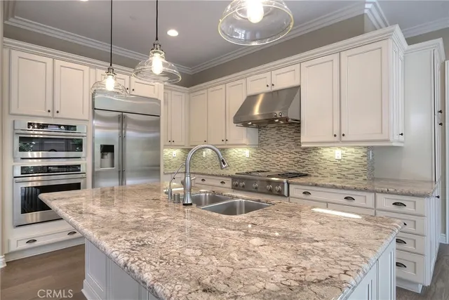 a kitchen with stainless steel appliances granite countertop a sink a stove and a refrigerator
