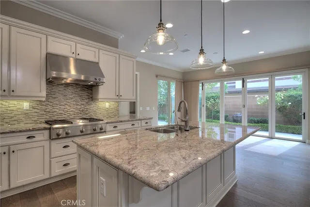 a kitchen with granite countertop a sink a counter space and stainless steel appliances