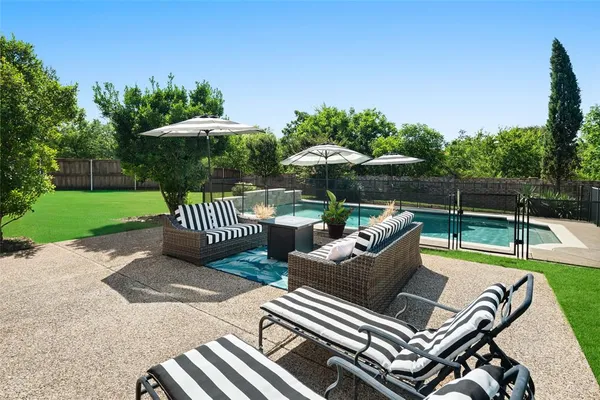 a view of a patio with couches table and chairs under an umbrella with a small yard
