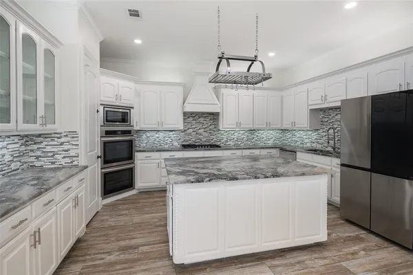 a kitchen with stainless steel appliances granite countertop a refrigerator a stove and a sink