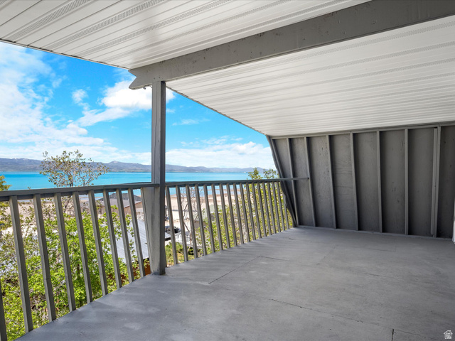 85 B Street, Unit 22 St. Charles, ID 83272 - Photo 32 of 35 Spacious covered balcony with concrete flooring, framed by a wooden railing and offering expansive water and mountain scenery
