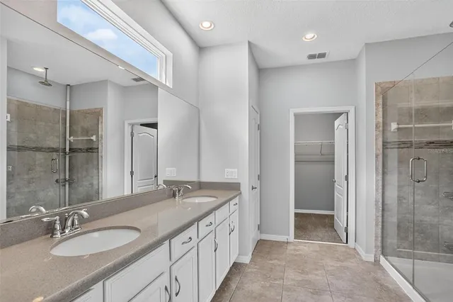 a spacious bathroom with a granite countertop double vanity sink mirror and shower