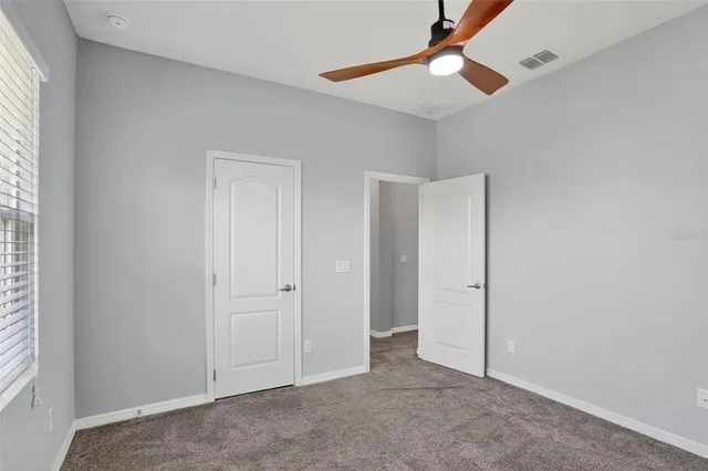 an empty room with fan and windows