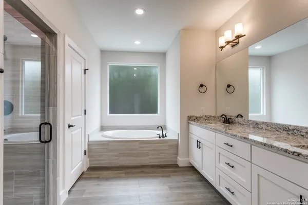 a bathroom with a granite countertop tub a double vanity sink and mirror