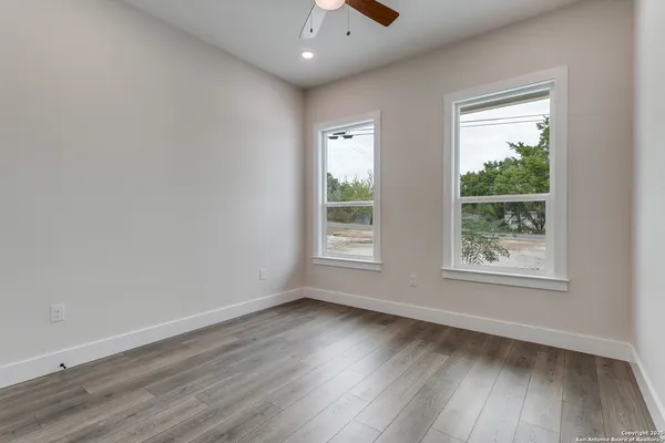 an empty room with wooden floor and windows