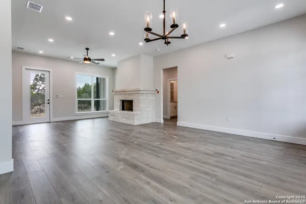 an empty room with wooden floor fireplace and windows