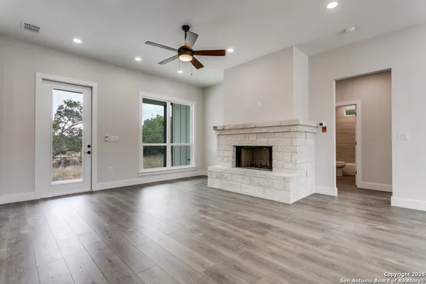 a view of an empty room with wooden floor fireplace and a window