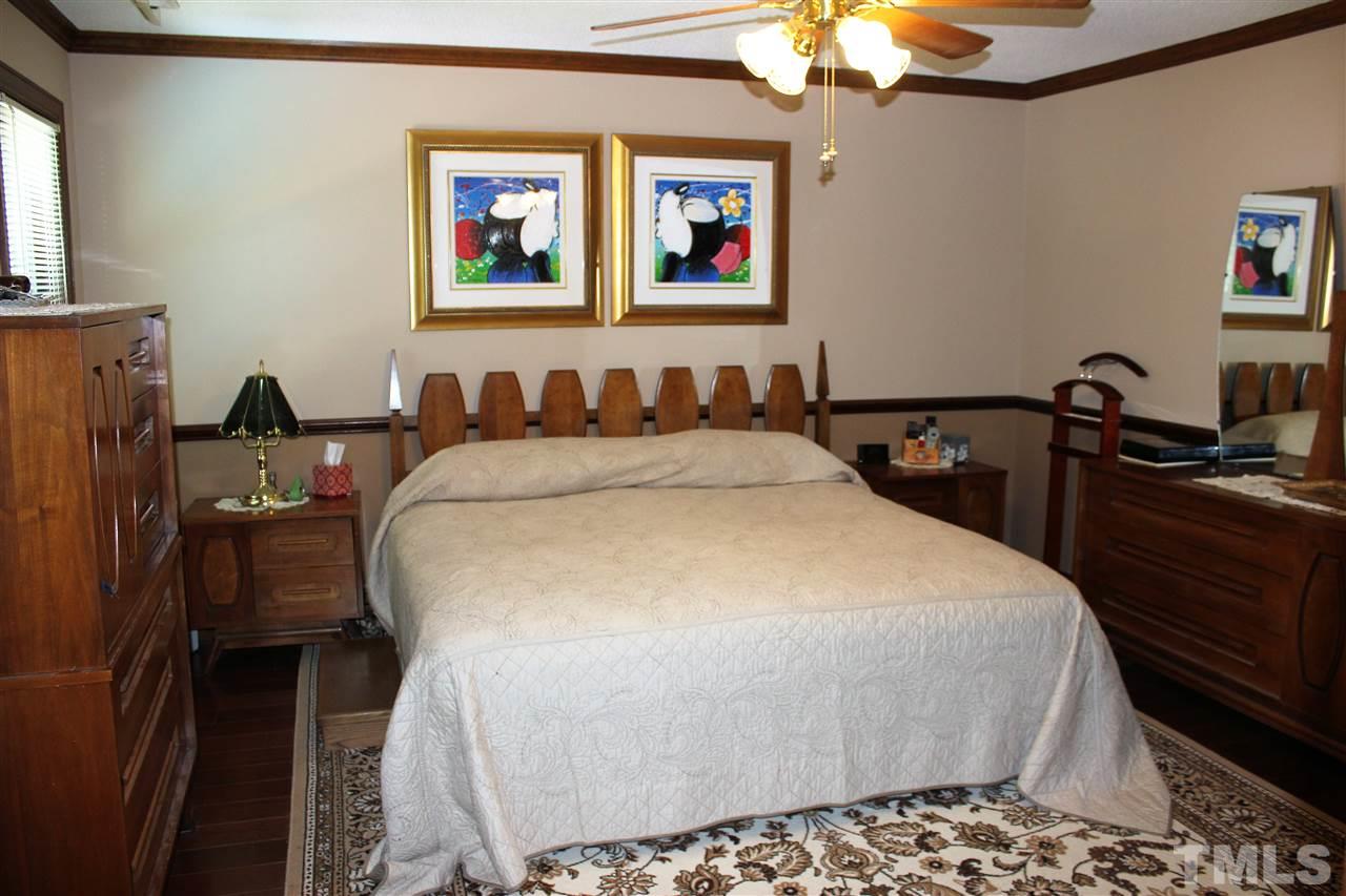 9504 Springdale Drive Raleigh, NC 27613 - Photo 11 of 25 a bedroom with a bed and a chandelier