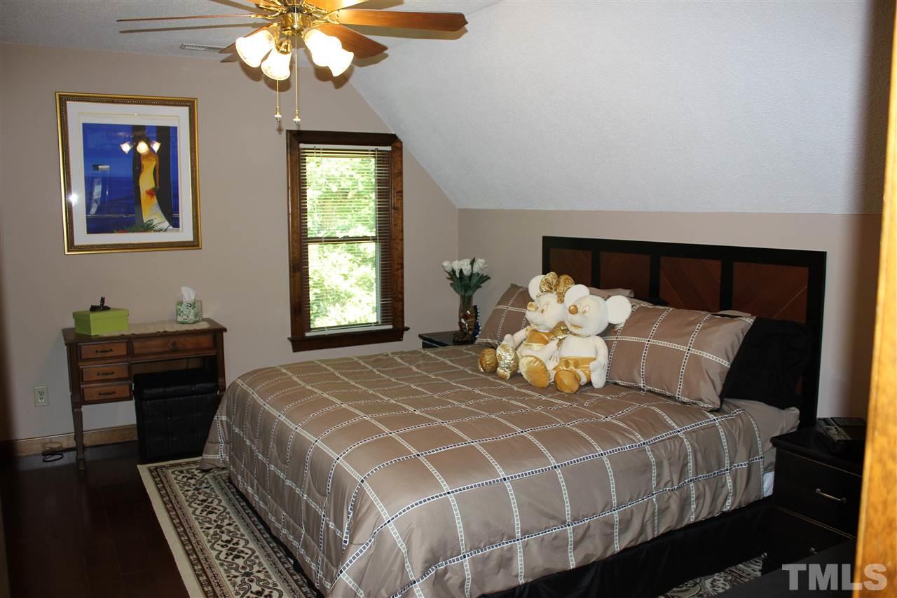 9504 Springdale Drive Raleigh, NC 27613 - Photo 14 of 25 a bedroom with a bed and a chandelier