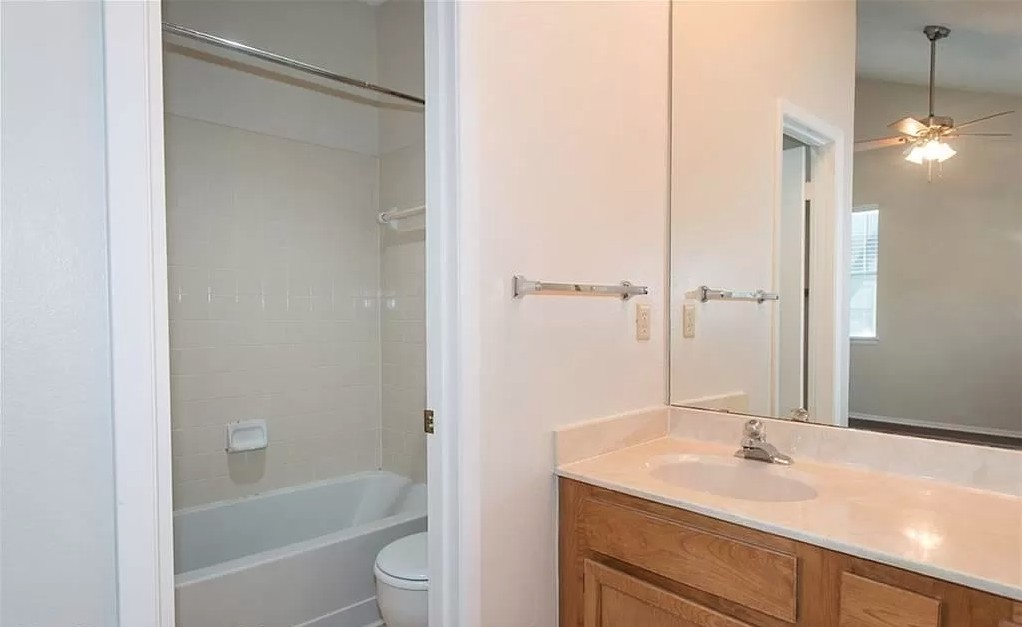 6501 Brush Country Road, Unit 102 Austin, TX 78749 - Photo 8 of 12 Clean-lined tile surround frames the built-in bathtub adjacent to a classic wood vanity setup.