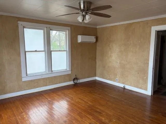 an empty room with wooden floor fan and windows
