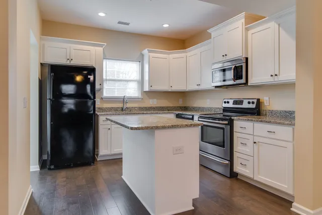 a kitchen with stainless steel appliances granite countertop a refrigerator and a stove top oven