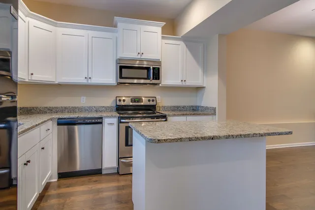 a kitchen with granite countertop white cabinets and white appliances