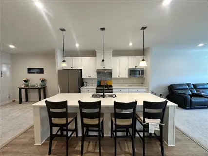 a kitchen with stainless steel appliances kitchen island granite countertop a dining table chairs and a refrigerator