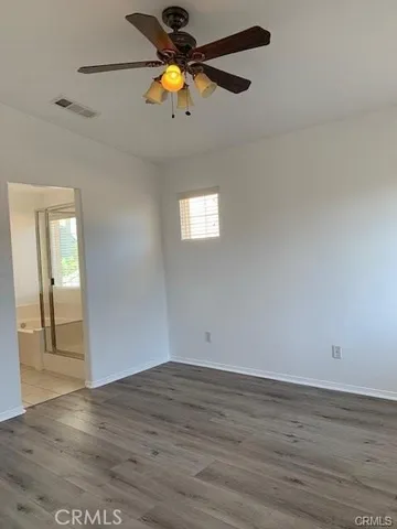 an empty room with wooden floor and chandelier fan