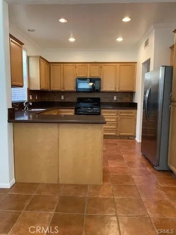 a large kitchen with stainless steel appliances a sink a stove a microwave a counter top space and cabinets