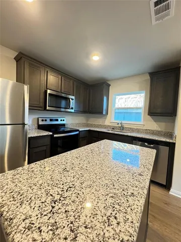 a kitchen with granite countertop a refrigerator and a sink