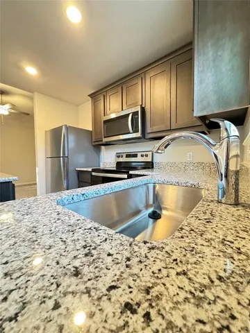 a kitchen with kitchen island granite countertop a sink and a stove top oven with wooden floor