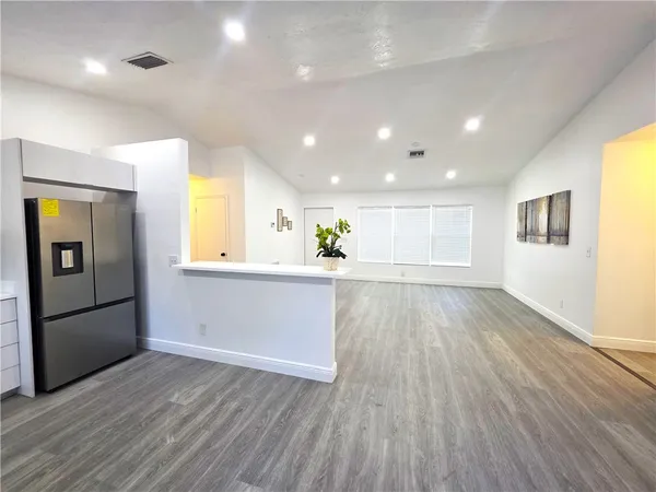a view of a kitchen with wooden floor and a refrigerator