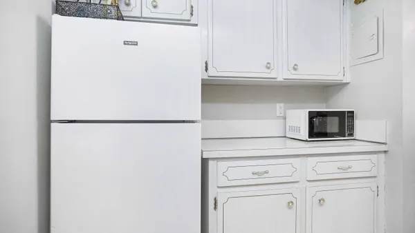a kitchen with white cabinets and a refrigerator
