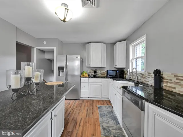 a large kitchen with granite countertop a large counter top appliances and cabinets