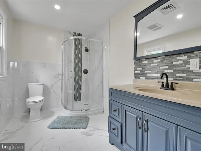 a spacious bathroom with a granite countertop sink a toilet a mirror and shower