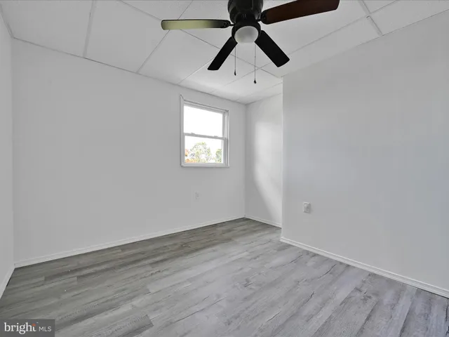an empty room with wooden floor ceiling fan and windows