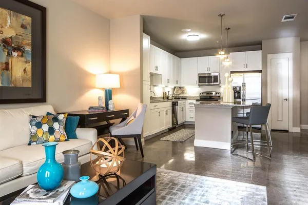 a kitchen with stainless steel appliances kitchen island granite countertop a dining table chairs stove a refrigerator and cabinets