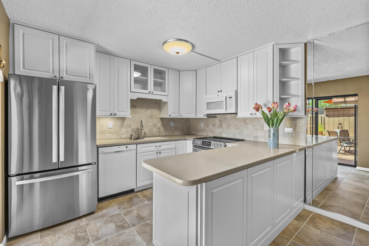 6025 Southeast Riverboat Drive, Unit 811 Stuart, FL 34997 - Photo 14 of 37 a kitchen with stainless steel appliances white cabinets and a refrigerator