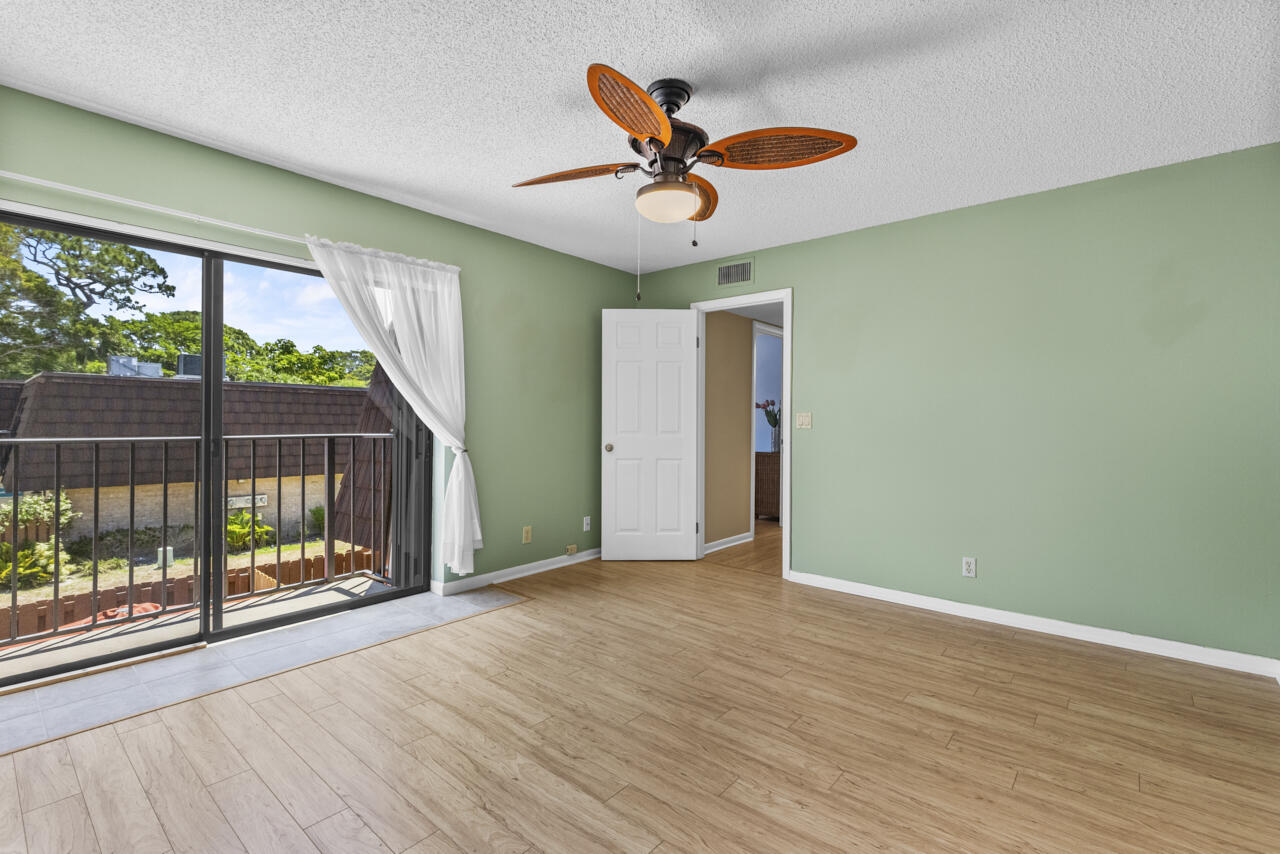 6025 Southeast Riverboat Drive, Unit 811 Stuart, FL 34997 - Photo 23 of 37 an empty room with wooden floor fan and windows