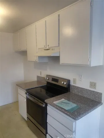 a kitchen with granite countertop white cabinets and a stove