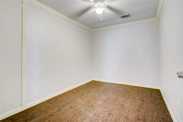 an empty room with a ceiling fan and wooden floor