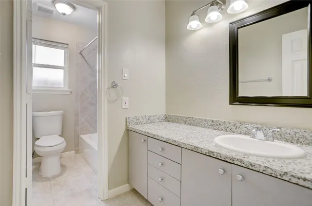 a bathroom with a granite countertop sink a toilet and a mirror