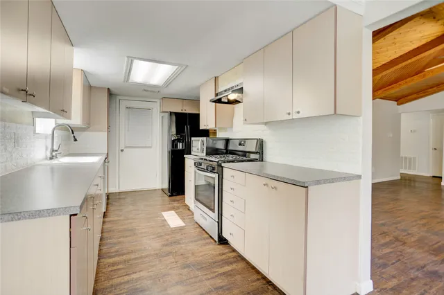 a kitchen with granite countertop a sink stainless steel appliances and cabinets