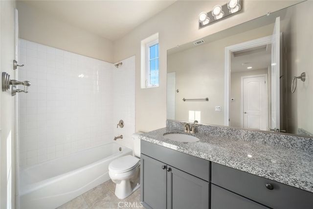 a bathroom with a granite countertop sink a toilet and shower