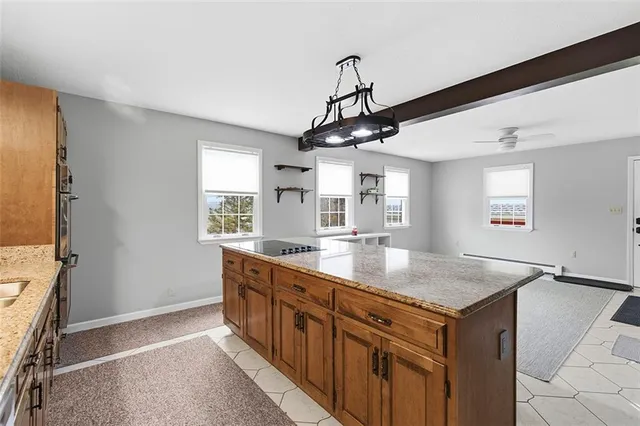 a hall with kitchen island granite countertop a sink appliances cabinets and a counter top space