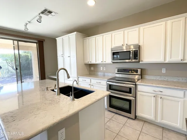 a kitchen with granite countertop a sink a counter top space appliances and cabinets